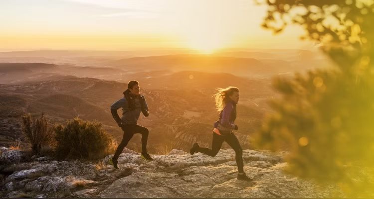 Two people running in the mountains at sunrise