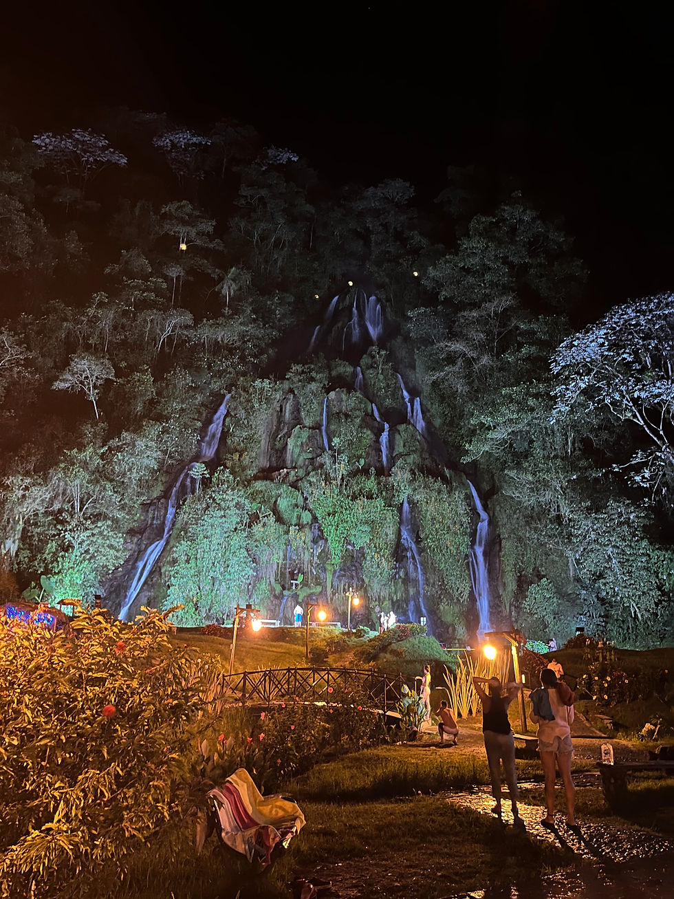 Massive jungle waterfall lit up at night.