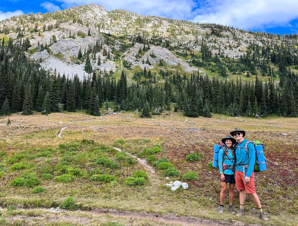 Two backpackers standing next to a dirt trail